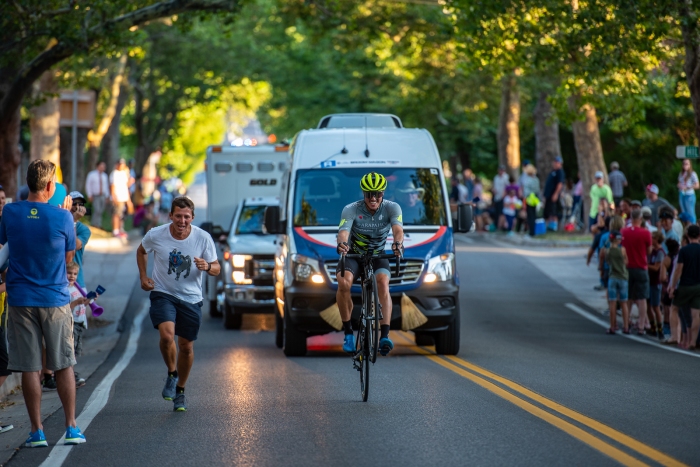 Miguel Bryon (Arapahoe-Hincapie p/b BMC) "races" a runner up State Street while holding a wheelie. Stage 4, 2019 Tour of Utah. Photo by Steven L. Sheffield