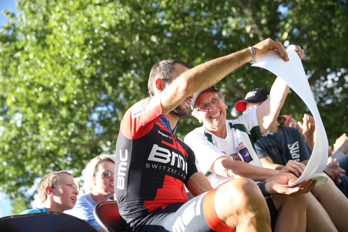 2018 National ITT Champion Joey Rosskopf of BMC Racing Team joins his family during the Team Presentation and checks out the poster given to him by the race.  2018 Tour of Utah Team Presentation, August 4, 2018, Cedar City, Utah. Photo by Cathy Fegan-Kim, cottonsoxphotography.net