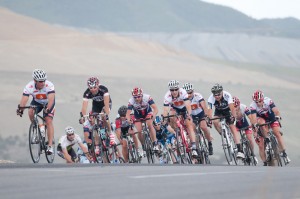 The Masters men's field rounds a corner with the Kennecott Copper Mine in the background. 